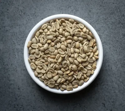 Bolivia FTO Colonial Caranavi green coffee beans in a white bowl on a dark tabletop