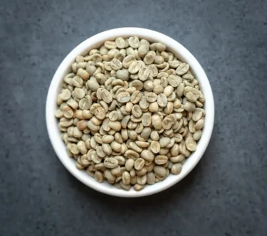 Bowl of Mexico Chiapas Fair Trade Organic Café Femenino green coffee beans on a dark surface