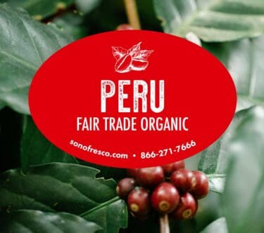 Peru Fair Trade Organic green coffee label over close-up of ripe red coffee cherries and green leaves