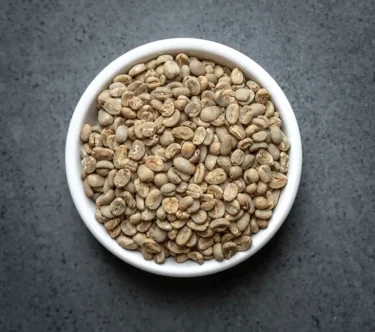 Bowl of Java Organic green coffee beans on a dark stone surface