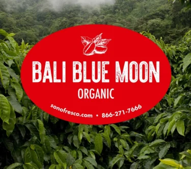 Bali Blue Moon Organic green coffee label over lush Indonesian coffee plants