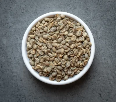 Bali Blue Moon Organic green coffee beans in a white bowl on a dark surface