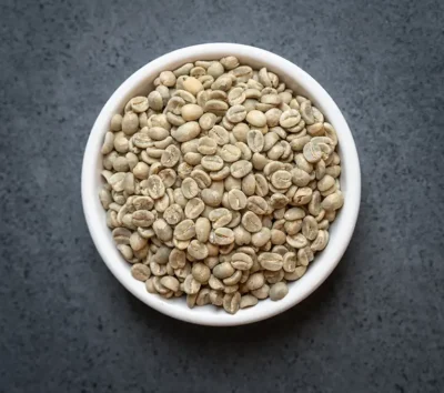 Bowl of Kenya AA green coffee beans on a dark surface
